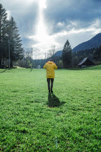 Rear view of man walking on grassy field