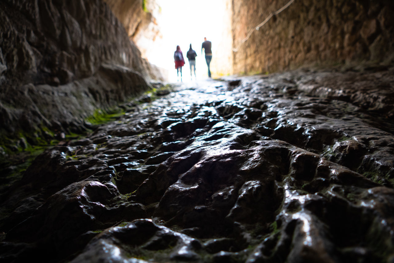 PEOPLE WALKING ON ROCK IN WATER