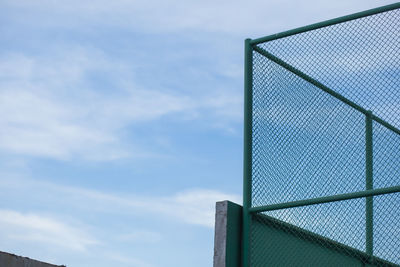 Low angle view of fence against cloudy sky