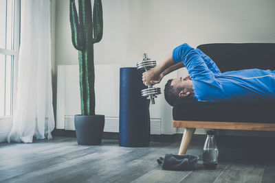 Man working out and trains at home. fit male doing exercise with weights for biceps. sport concept