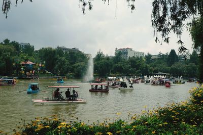 People on boats in lake against sky