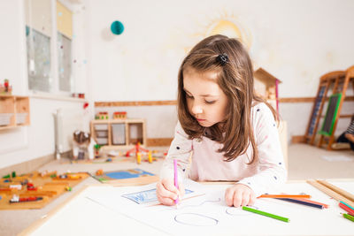 Girl looking away while sitting on table at home