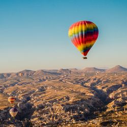 Hot air balloons flying over landscape against clear sky