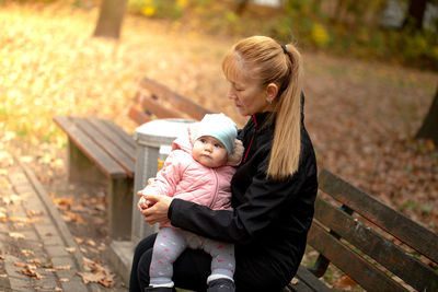 Full length of mother and woman on bench