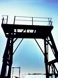 Low angle view of silhouette bridge against clear blue sky