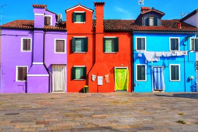 Multi colored houses by street against blue sky