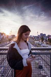 Beautiful woman standing by cityscape against sky