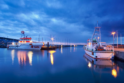 Boats moored at harbor against sky at dusk