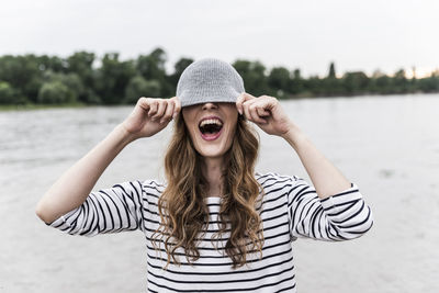 Portrait of woman wearing hat standing at beach