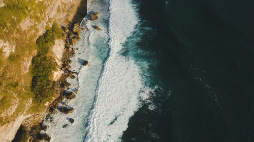 Aerial view of rocky coast with surf the waves off the at sunset, bali,indonesia, pura uluwatu cliff