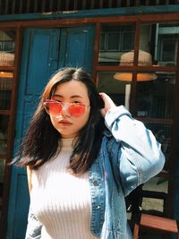 Portrait of beautiful young woman standing against building