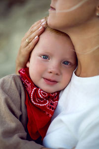 Mom hugs tired child son with red scarf on the street