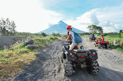 People riding motorcycle on road against sky