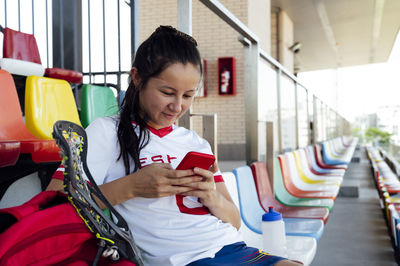 Smiling player text messaging using smart phone at stadium