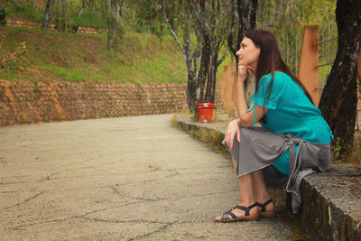 Side view of woman sitting on footpath
