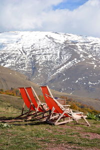 Empty red deck chairs against snowcapped mountains