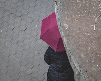 Low section of person with umbrella standing on rainy day