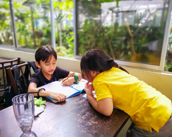 Rear view of siblings sitting on table