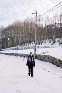 Rear view of man walking on snow covered field