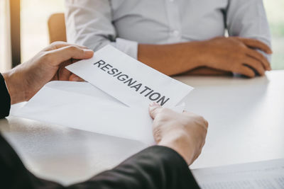 Midsection of man holding paper with text on table