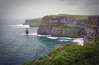 Scenic view of sea by cliff against sky