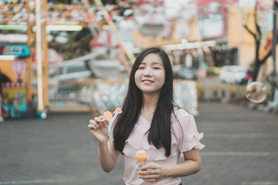 Portrait of young woman holding bubble wand at amusement park
