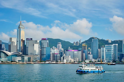 Ship in sea against modern buildings in city