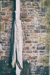 Cloth hanging from pipe against brick wall