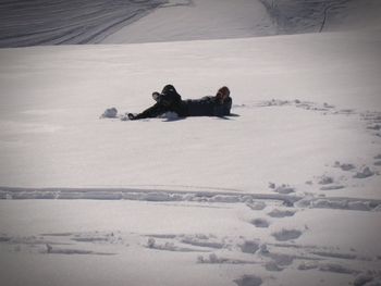 Person lying on snow covered land