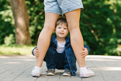 Three year old son is sitting between the legs of his standing mother. the concept of parental