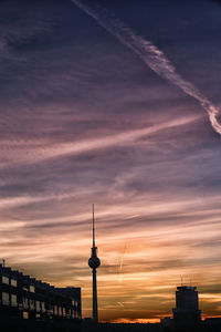 Communications tower in city at sunset