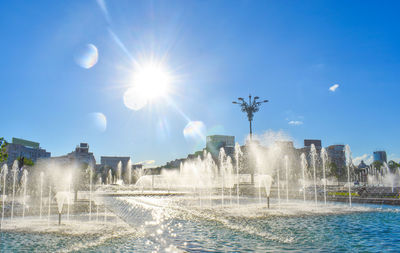 Water fountain in swimming pool against sky on sunny day