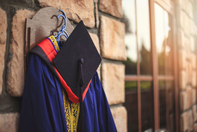 Graduation gown with mortarboard hanging on wall