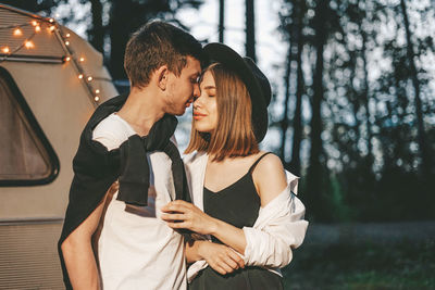 Young couple standing against trees