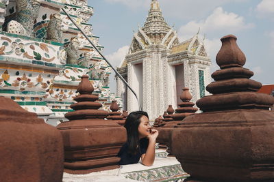 Smiling young woman standing by temple