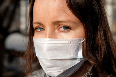 Close-up portrait of woman wearing scarf and knit hat outdoors during winter