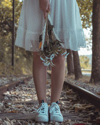 Low section of woman standing on railroad track