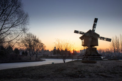 Traditional windmill on field against sky during sunset