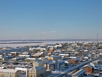 High angle view of townscape by sea against clear sky