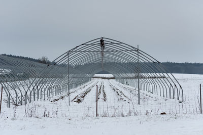 Fence on snow covered field against sky