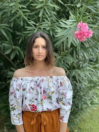 Portrait of beautiful young woman standing against plants