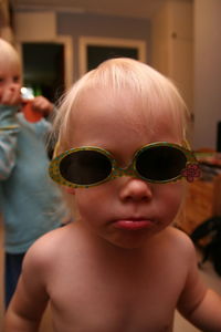 Close-up portrait of shirtless girl wearing sunglasses while standing at home