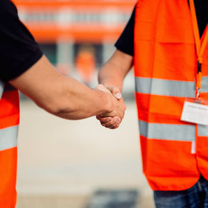 Midsection of workers handshaking