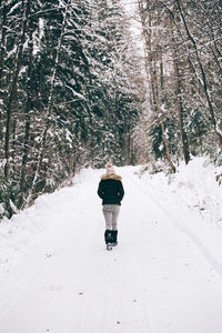 Rear view of man on snow covered road