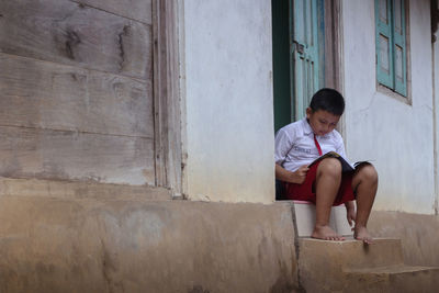 Boy reading book at doorway