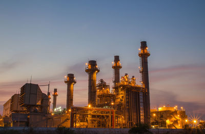 Low angle view of illuminated factory against sky at night