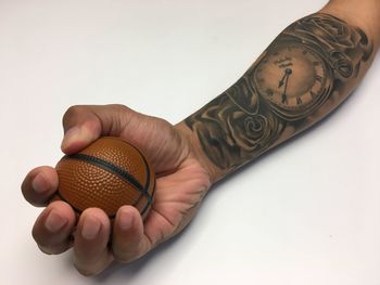 Close-up of man holding ball against white background