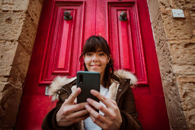 Portrait of smiling young woman using mobile phone