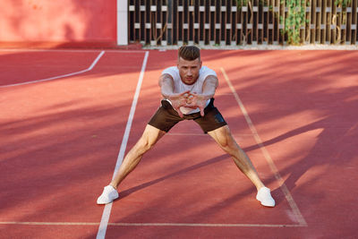 Full length of young woman exercising on field