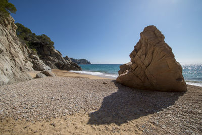 Rock formation on beach against clear sky